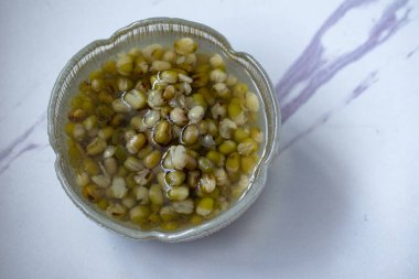 Yeşil fasulye, gri arka planda cam bir fincanda kaynatılmış şeker.