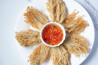 Beyaz tabakta baharat soslu çıtır altın iğneli mantar.