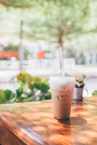ahşap masa ağaç arka planda plastik bardakta süt kahve Iced