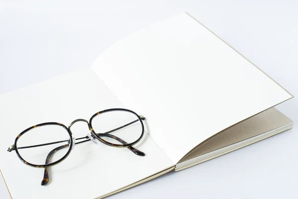 Glasses on white page of opened notebook, white background — Stock Photo, Image