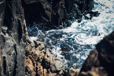 Köpüklü su kayalara sıçrar.