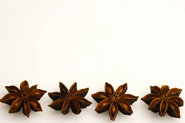 The four anise stars are in a row at the bottom of the frame on a clean white clipping background. There is empty space above them for the inscription. Close-up photographed.