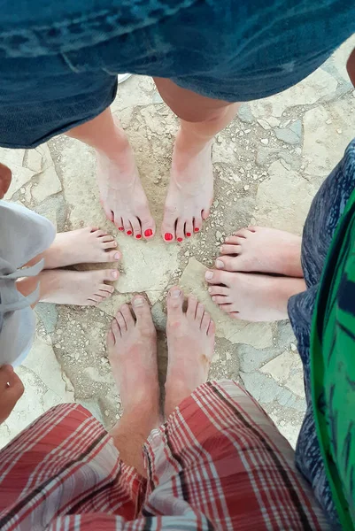 Four pairs of legs of people of different ages and genders are shot from above in the summer — Stock Photo, Image