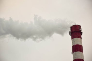 Buğulu çizgili bir bitki bacası ya da gökyüzü arka planında bir fabrika.