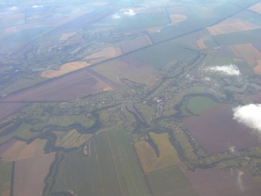 Dünya yüzeyi uçağın yüksekliğinden alındı. Aşağıda - kara parselleri bulutların arka planına karşı parçalara bölünmüş
