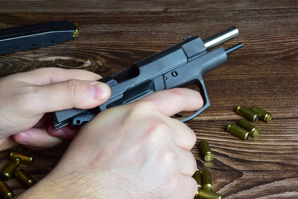 Em um fundo de madeira, há muitos cartuchos espalhados, bem como uma mão recarregando uma pistola. — Fotografia de Stock