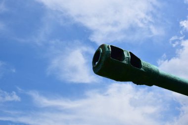 Çerçevenin sağ tarafında, bir tankın ya da topun namlusu parlak mavi bir gökyüzüne dönüşür. Sol tarafta yazıt için boş bir alan var.