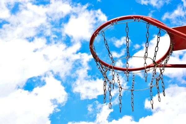 Κοντινό πλάνο ενός μπάσκετ στεφάνι στη δεξιά πλευρά ενάντια σε ένα φωτεινό μπλε ουρανό. Στην αριστερή πλευρά υπάρχει ένας κενός χώρος για την εισαγωγή κειμένου — Φωτογραφία Αρχείου