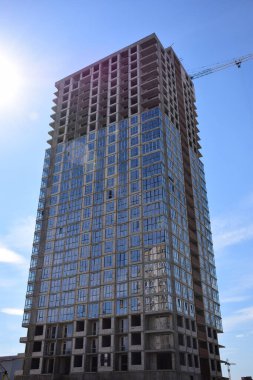İnşaat halindeki bir gökdelen ve mavi gökyüzüne karşı bir kule vinci.