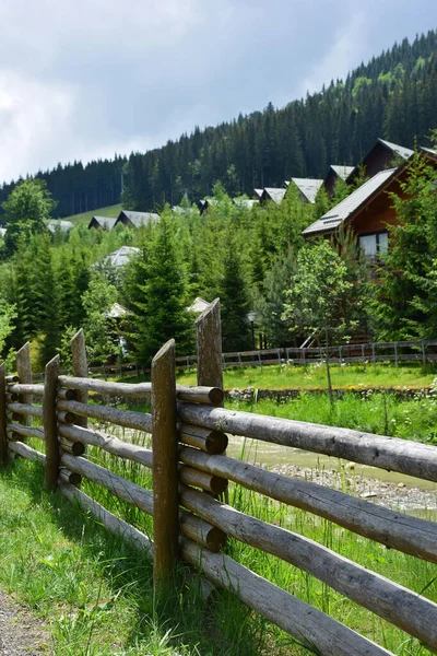 Ett gammalt staket gjort av stockar nära en liten flod och ett antal hus och ett antal träd — Stockfoto