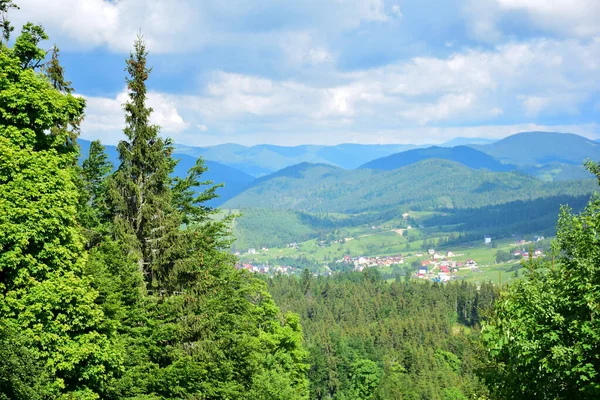 Landschappelijk uitzicht van de berg naar het dorp tussen de bergen bedekt met bos. Uitzicht vanuit de verte — Stockfoto