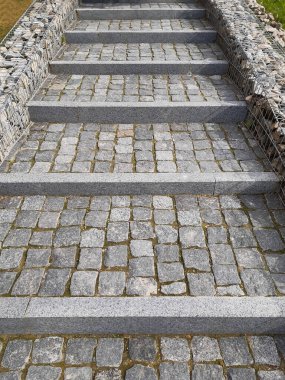 Sırayla dizilmiş fayanslı taş kaldırım basamakları, kayalarla süslenmiş sınırlarla perspektif bırakarak