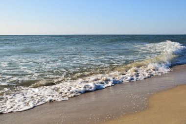 Deniz dalgaları kumlu gündüz kumsalında dalgalanır