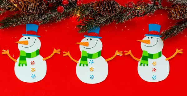 Kırmızı arka planda Noel kardan adamı, çelenk. Ağaçların dalları, ışıkları... Yukarıdan manzara. Yılbaşı konsepti.