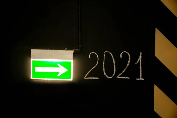Green emergency exit sign or fire exit sign showing the way to New year 2021, arrow symbol. The concept of Christmas, holiday.