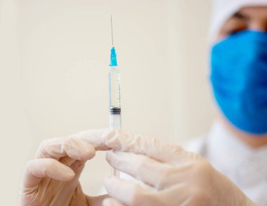 Covid-19 Corona virüsüyle mücadele konsepti, bir kız doktor içinde çocuklar ve yaşlılar için sıvı aşılar bulunan bir şırınga taşıyor..