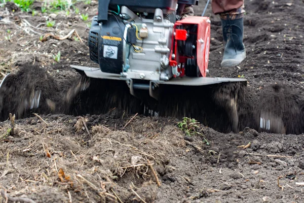 Homem Fazendeiro arado a terra com um cultivador. Máquinas agrícolas: cultivador de lavoura no jardim, motor cultivador. — Fotografia de Stock