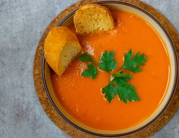 Soupe à la citrouille et aux carottes avec crème et persil sur fond de béton foncé, vue de dessus de l'espace. — Photo