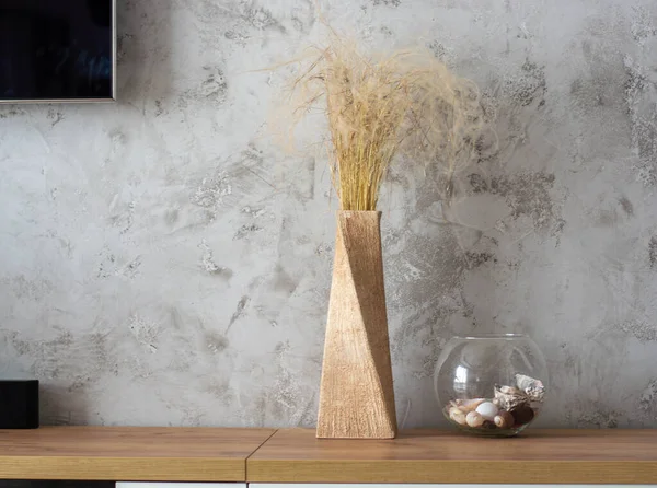 Hierba seca en un elegante jarrón de arcilla sobre un fondo de hormigón. Diseño en el estilo del minimalismo. Imagen de stock
