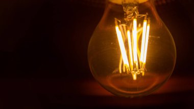 Koyu arkaplanda asılmış eski bir ampul. Çatı katı biçimi.