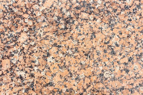 Abstract textured red granite background. Close-up view. Construction industry. Granite is rocks that is composed mostly of coarse-grained quartz and feldspars in varying proportions.