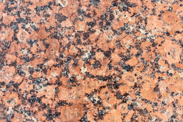 Abstract textured red granite background. Close-up view. Construction industry. Granite is rocks that is composed mostly of coarse-grained quartz and feldspars in varying proportions.