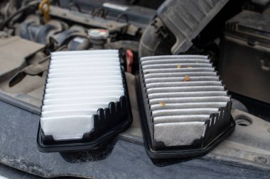 Araba motorunun hava filtresi değiştiriliyor. Fotoğraf eski ve yeni bir filtreyi gösteriyor. Filtreler arabanın motor bölümündedir..