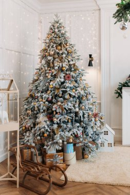 Noel süsleriyle süslenmiş bir Noel ağacının fotoğrafı (toplar, yıldızlar, kar taneleri), ağacın altında hediyeler..