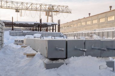 İnşaat için güçlendirilmiş beton yapıların üretimi için bir fabrikanın deposunda güçlendirilmiş beton yığınları var.