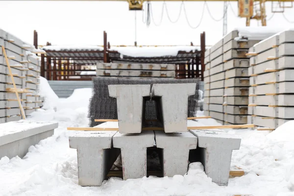 Reinforced concrete beams in the warehouse of the plant, ready for shipment. End view. The season is winter.