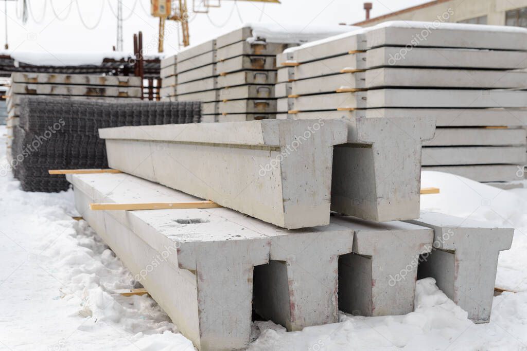 Warehouse for reinforced concrete products in winter. Reinforced concrete foundation beams for building construction.
