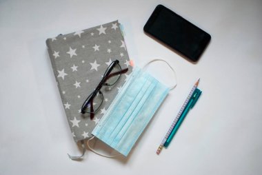 Not defteri, gözlük ve beyaz bir maske.