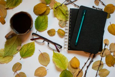 E-kitap, bardak ve kahve beyaz arka planda yapraklarla