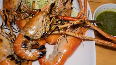 Izgara karides deniz ürünlerinde hafif siyah yanık var. Restoranda beyaz bir tabağa koy..