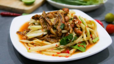 Mango fotografı üst görünüm yiyecek düzenlemesi. Baharatlı salata yemeği, üzerine kızarmış fındık ve çıtır balık. Ana malzemeler çiğ mango, limon suyu, taze acı biber tozu, balık sosu, karıştırmak için şeker. Bırak ekşi tadı getirsin.