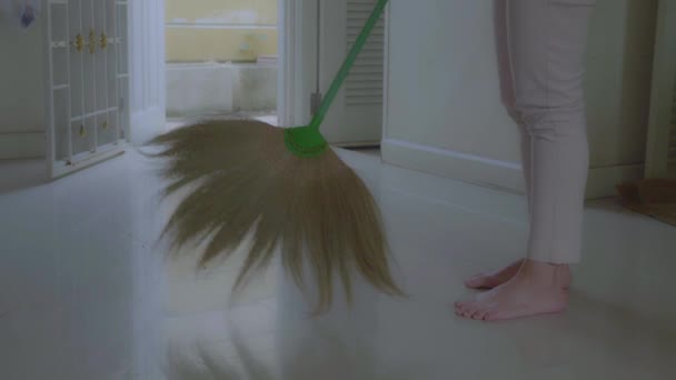 女性はほうきで家の中を掃除します 草のほうきでアジア風の家の掃除 — ストック動画