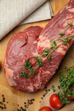 Tahtada baharat ve otlarla dilimlenmiş çiğ et parçaları. 