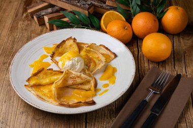 Portakal reçelli krep ve büyük beyaz tabakta dondurma.