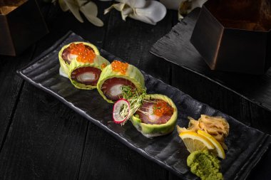 Somonlu suşi, avokado, salatalık, domates, peynir, siyah arka plan, üst görünüm.