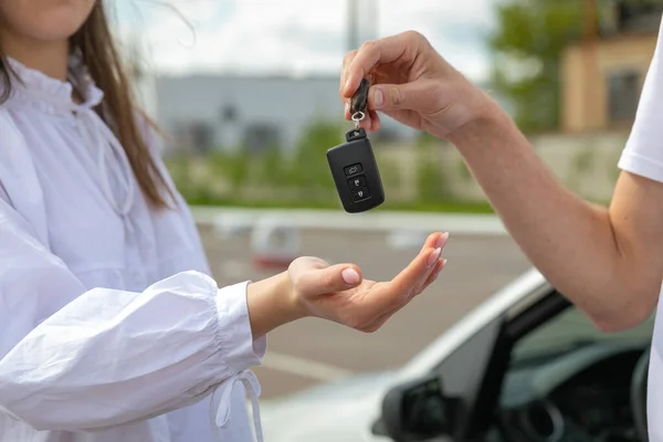 woman holding car keys and key in hand