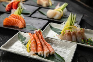 Karanlık bir masada çeşit çeşit saşimi.