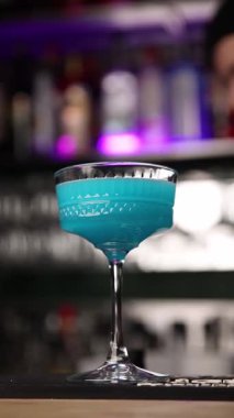 Barmen barın arkasında kokteyl yapar..