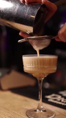 Barmen barın arkasında kokteyl yapar..