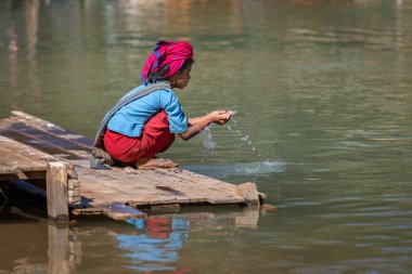 Inle Gölü, Myanmar - Aralık 2019: Nehir kıyısında oturan kız 
