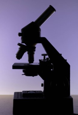 Laboratuvar biyolojik mikroskobunun siluetinin görüntüsü, yan taraftan görülüyor..