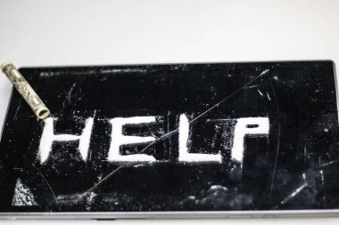 Karanlık bir yüzeyde, bir uyuşturucu bağımlısı tarafından yazılmış toz kokain ve bir şeridin başına konmuş bir dolar banknotunun fotoğrafı.