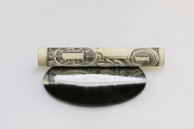 Yuvarlak bir aynaya yerleştirilmiş kokain tozunu çekmek için sarılmış bir doların yakın plan fotoğrafı.