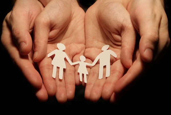 A paper family holding hands, in the hands of the woman and the man who hold out, with the concept of conceiving a child and creating a family.