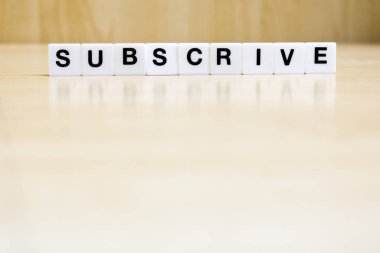   Abone kelimesini oluşturan harfleri içeren bir sıra küçük beyaz plastik karo, bir şeye abone olma kavramını temsil ediyor..