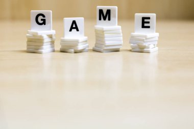    Oyun konseptini temsil etmek için oyun kelimesini oluşturan harfleri içeren bir sıra küçük beyaz plastik karo..